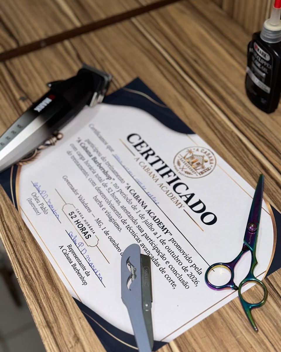 Certificado da A Cabana Academy na bancada, com máquina, navalha e tesoura